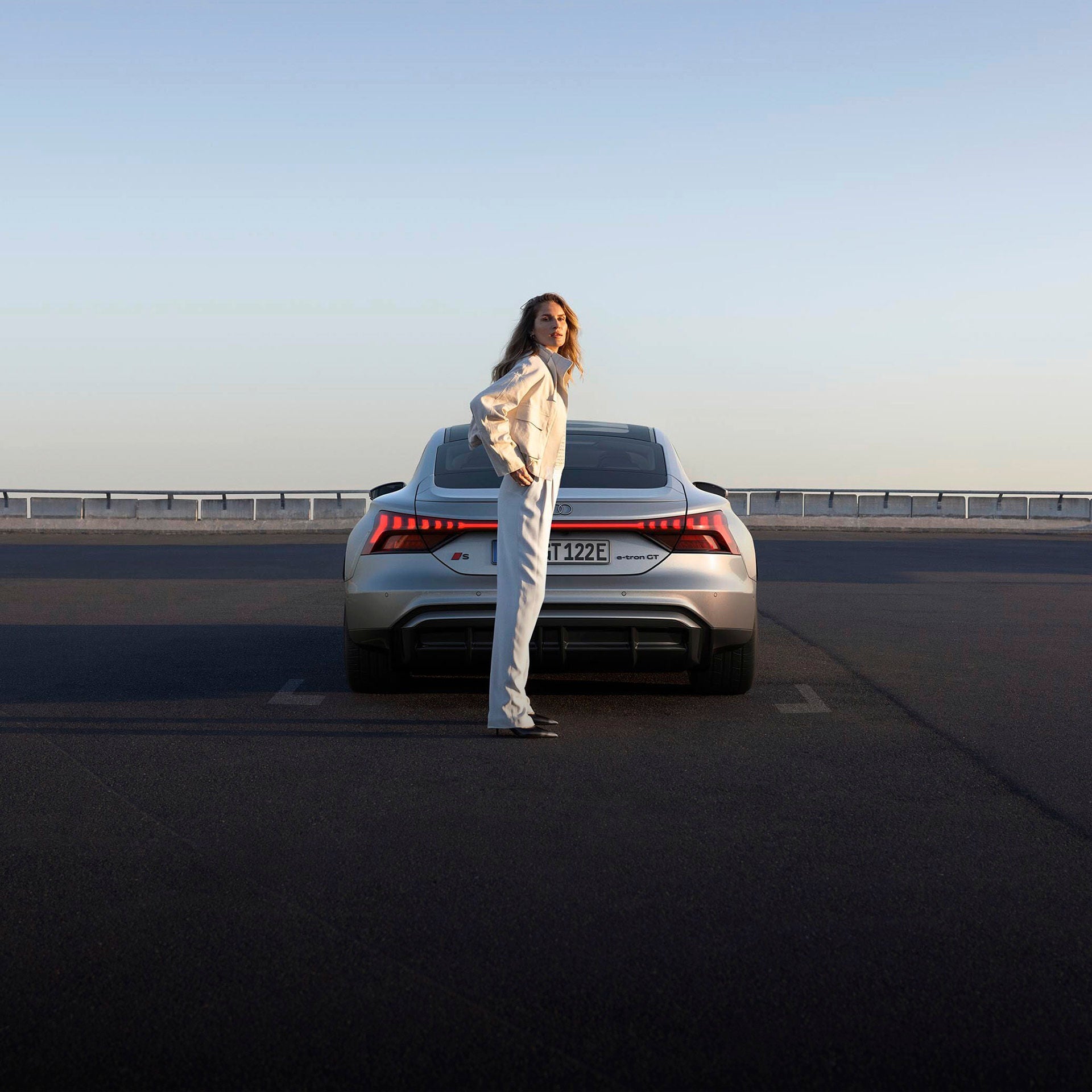 Un coche Audi eléctrico en un aparcamiento con una mujer. 