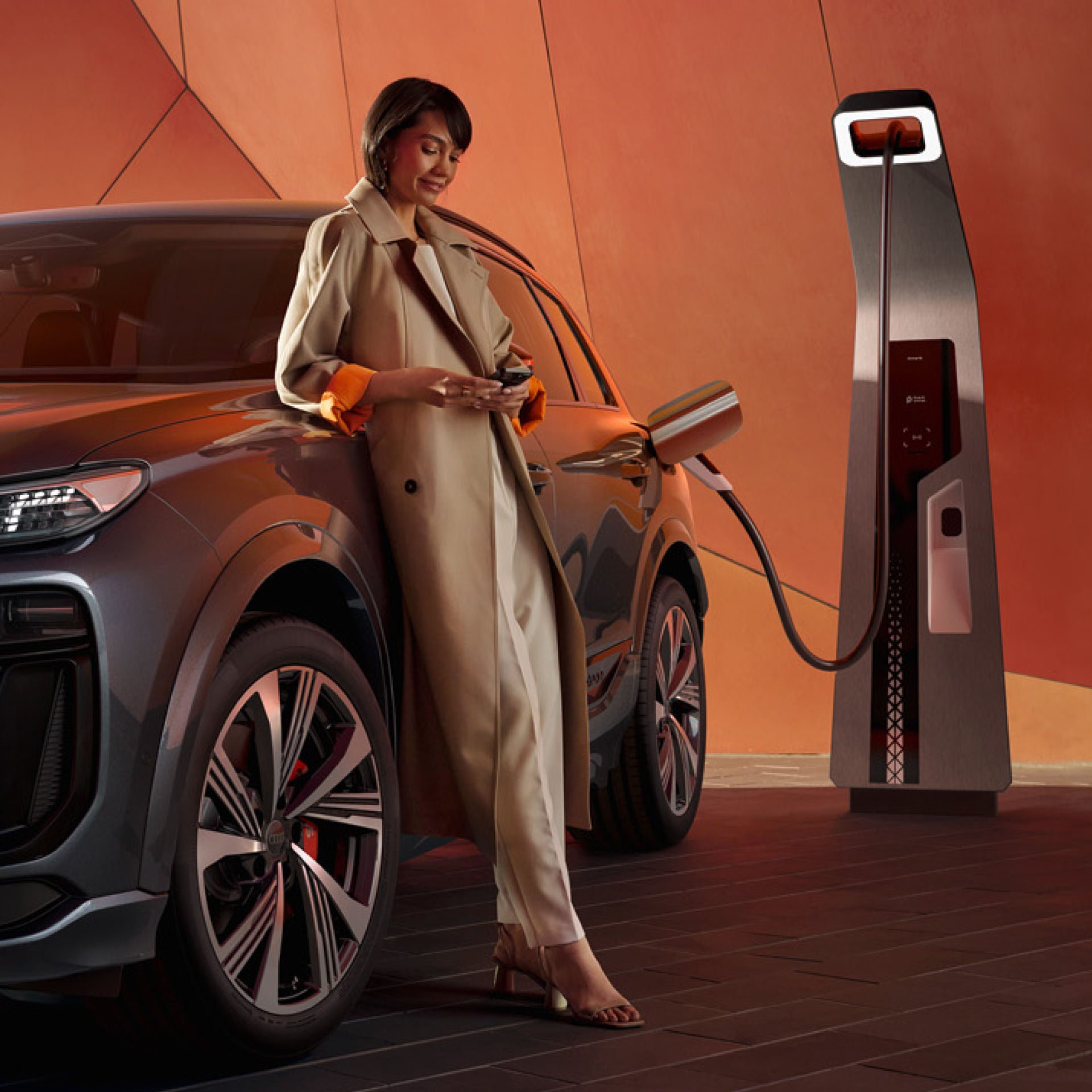 A person in a trench coat charging an electric SUV at a charging station.