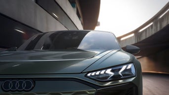 Close-up of a sleek green Audi sports car in a tunnel, sunlight reflecting on its shiny surface. The scene conveys speed and modern sophistication.
