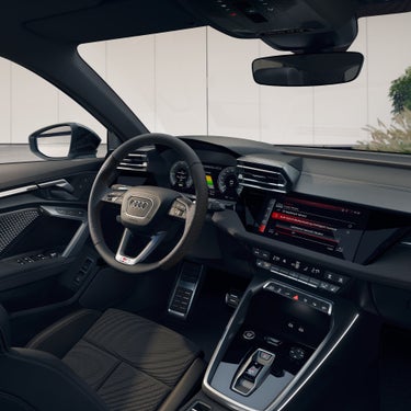 Innenraum eines Audi A3 Sportback TFSI e mit Lenkrad, digitalen Instrumenten und großem Infotainment-Display im Tageslicht.