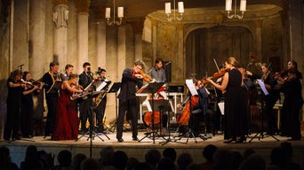 Kammerorchester O/Modernt mit Dirigent Hugo Ticciati bei einem Konzert auf einer festlich beleuchteten Bühne mit Streich- und Blasinstrumenten.