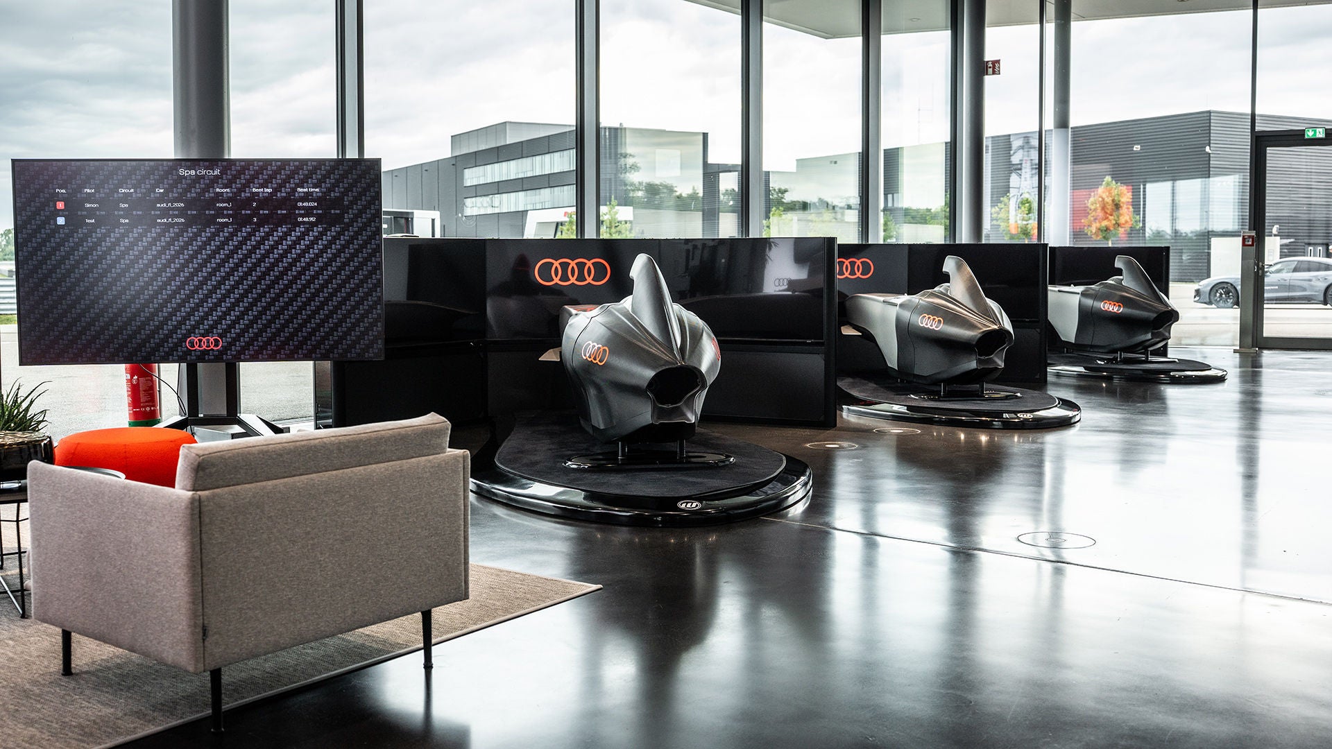 Schrägansicht eines silber-schwarzen Formel-1-Rennwagens mit roten Akzenten vor grauem Hintergrund, Audi- und Revolut-Logo in schwarz am Rand.