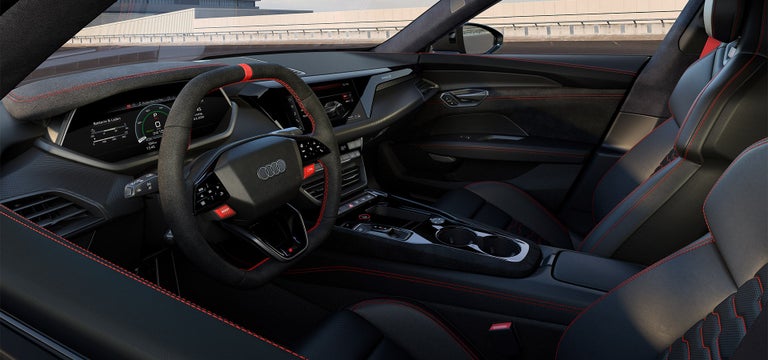 Innenraum eines Audi RS e-tron GT mit schwarzem Alcantara-Lenkrad, roten Nähten und digitalen Displays.