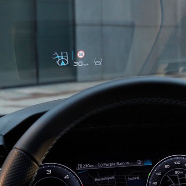 View of a car's head-up display projecting speed and navigation icons onto the windshield.