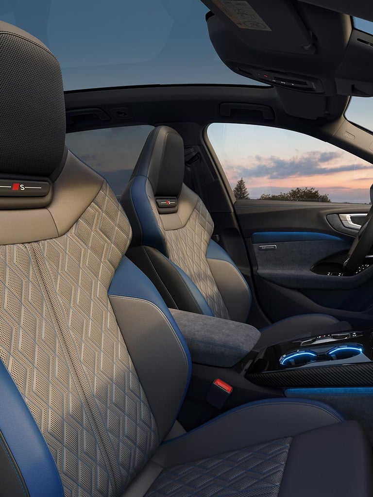 Innenraum des Audi A5 Avant mit Sportsitzen in Rautensteppung, blauen Akzenten und großem Touchdisplay.