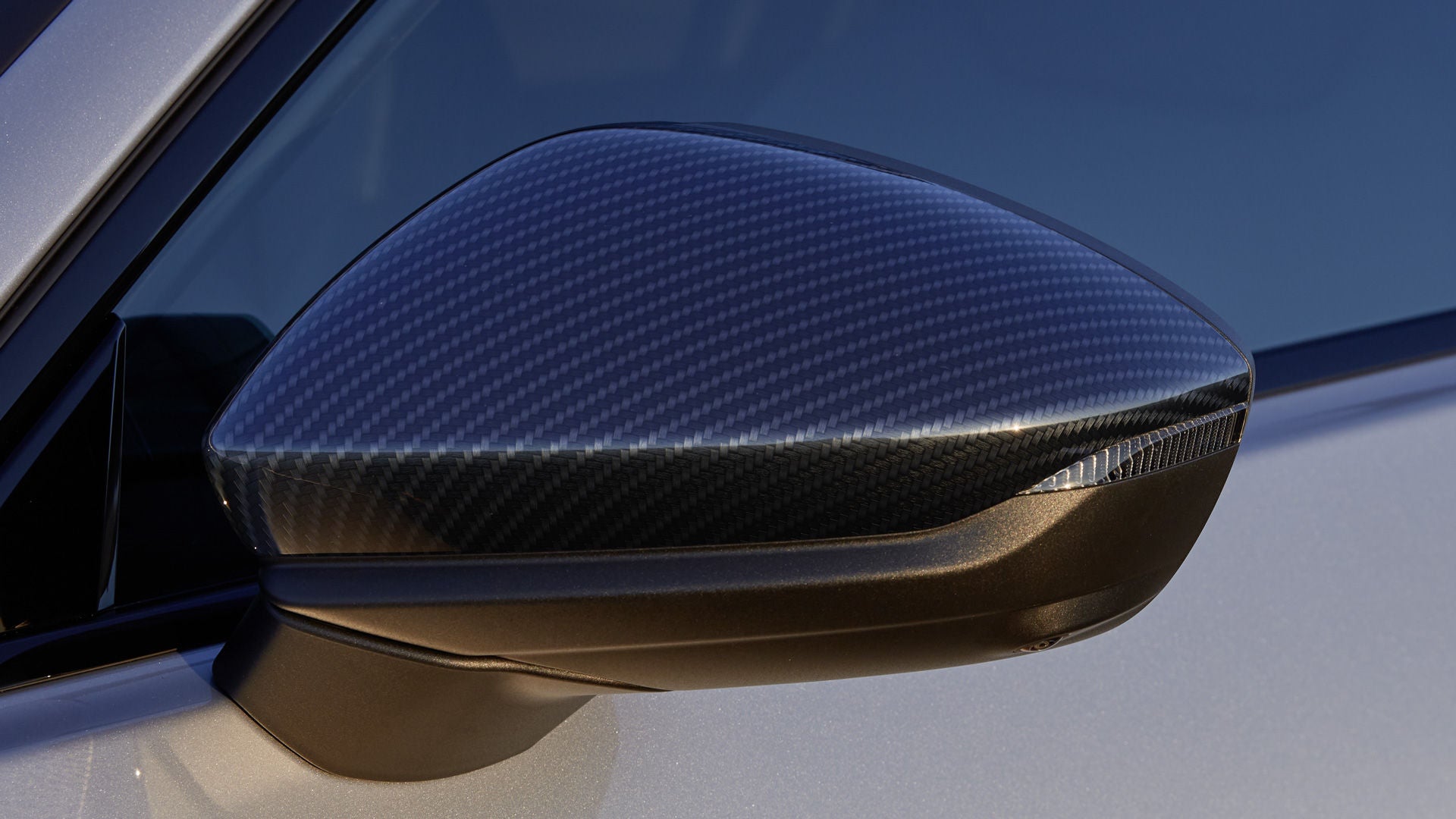 Nahaufnahme des linken Außenspiegels mit einem Gehäuse in Carbon.