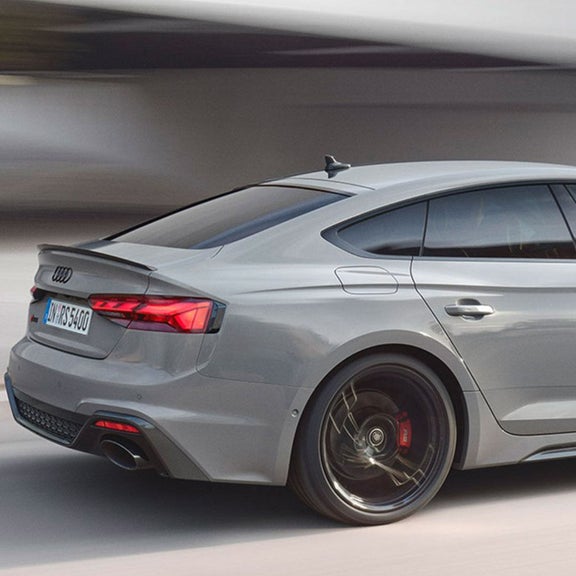 Silver car in motion with background blur, showcasing speed and design.