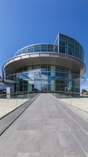 Rundes Glasgebäude bei klarem, blauem Himmel, modernes Design mit reflektierenden Fassaden.