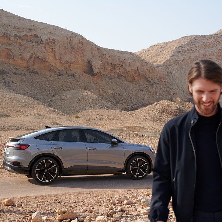Ein Mann läuft von einem Audi weg in einer Wüsten-Landschaft.
