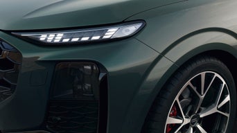  A grey Audi vehicle parked diagonally in an empty outdoor car park, viewed from above