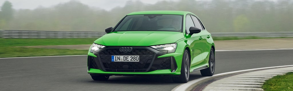 Hellgrüner Audi RS 3 Sportback fährt auf Rennstrecke (Frontansicht).