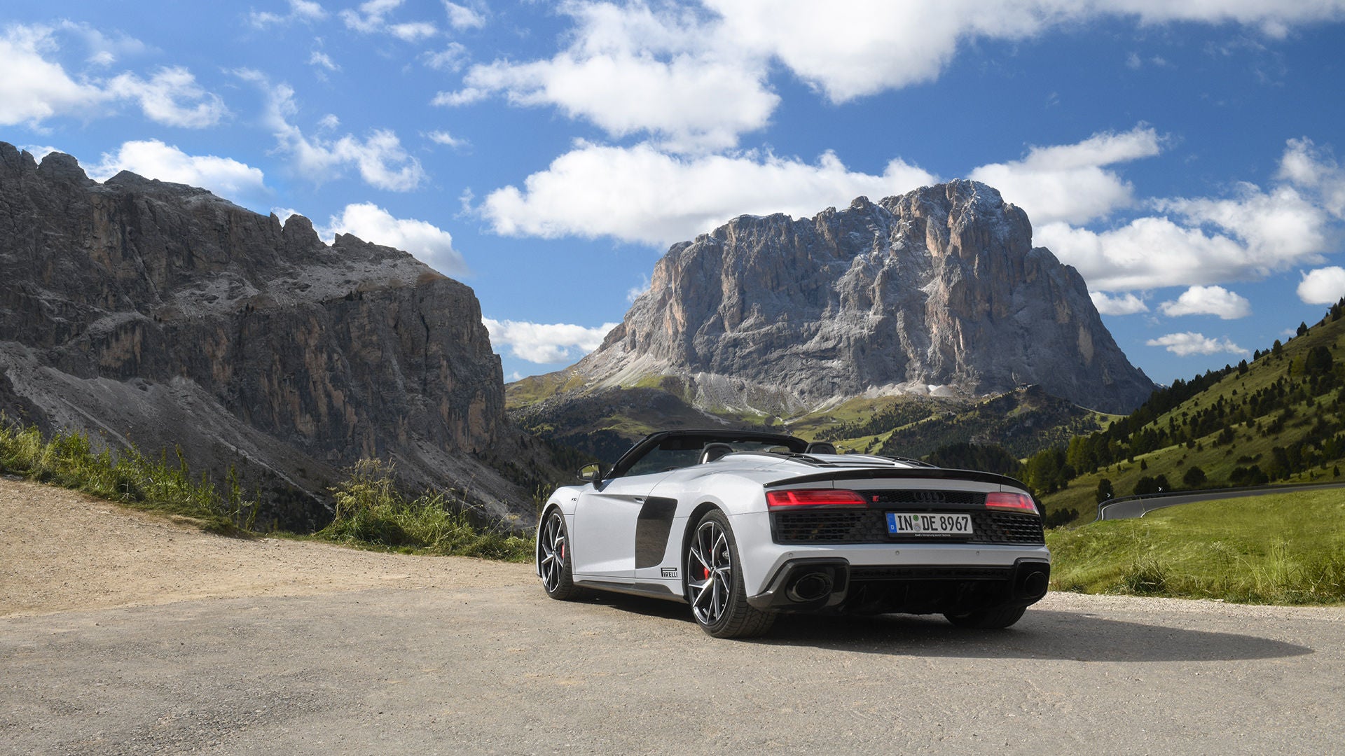 White Audi R8 Spyder V10 performance quattro with open top (rear view) standing in the mountains in great weather