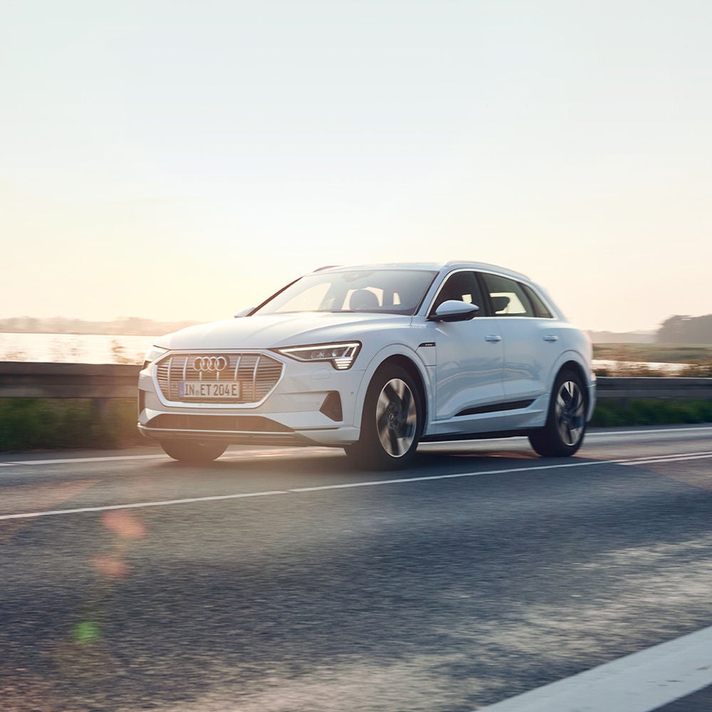 Audi e-tron drives along the low-lying sun.