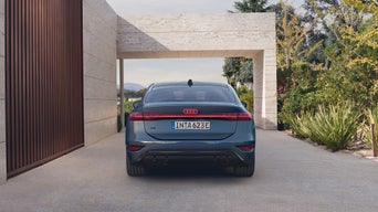 Vue arrière d’un SUV électrique devant une entrée de propriété.