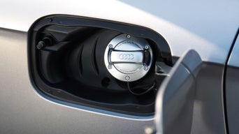 Geöffnete Tankklappe eines silbernen Audi mit silbernem Tankdeckel und Audi-Ringen.