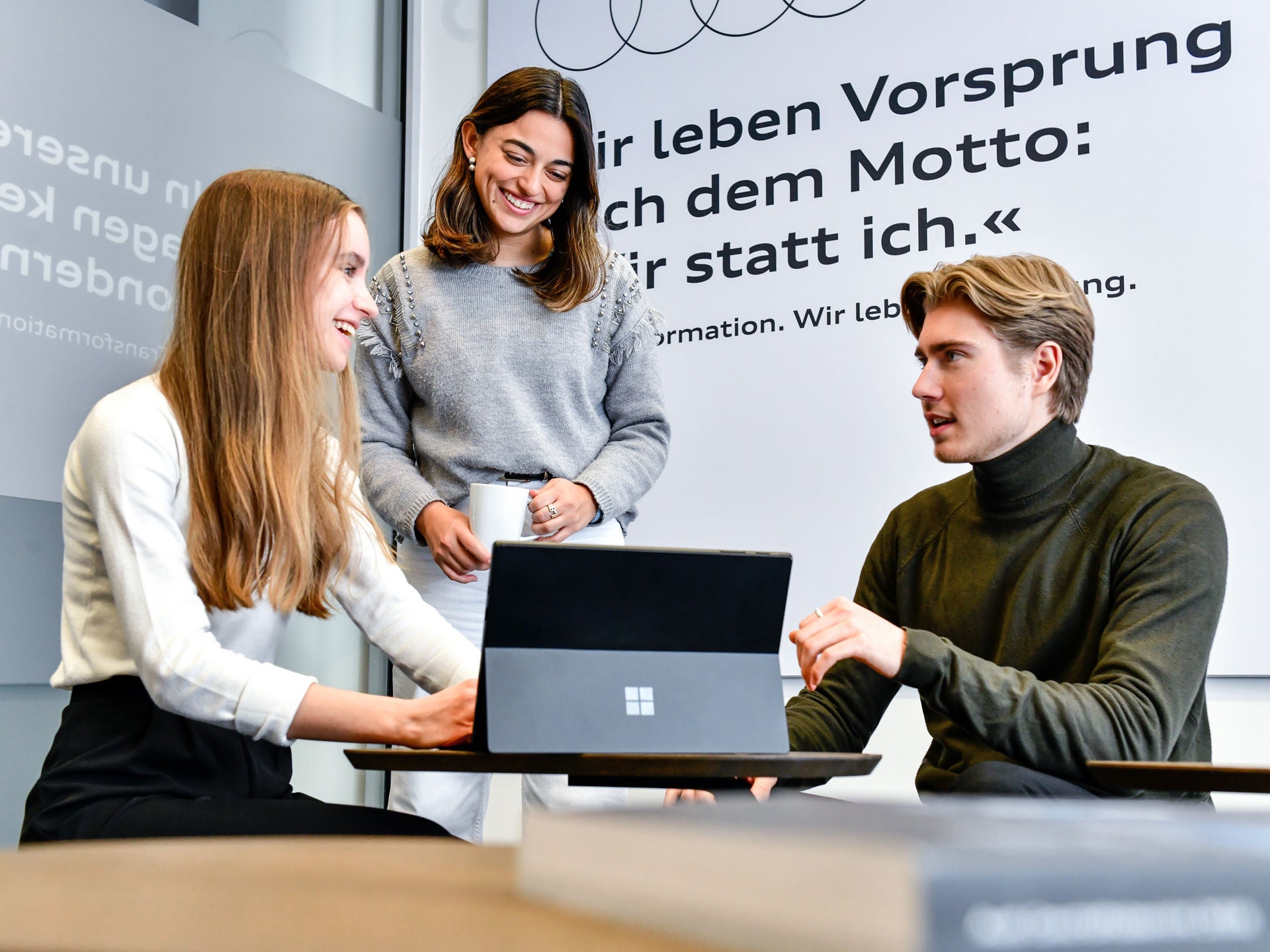 Drei Studenten sitzen an einem Tisch und reden miteinander