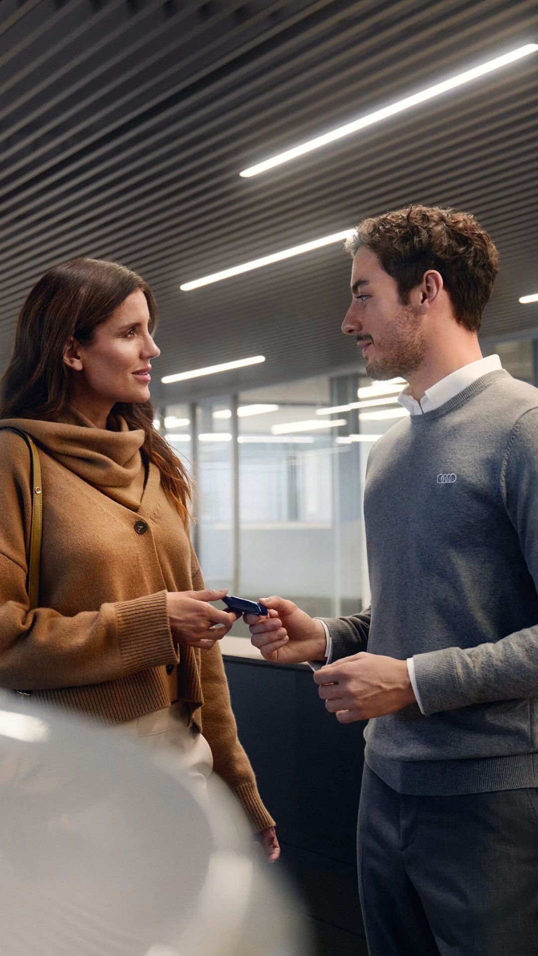 Uomo consegna una chiave a una cliente in showroom auto.