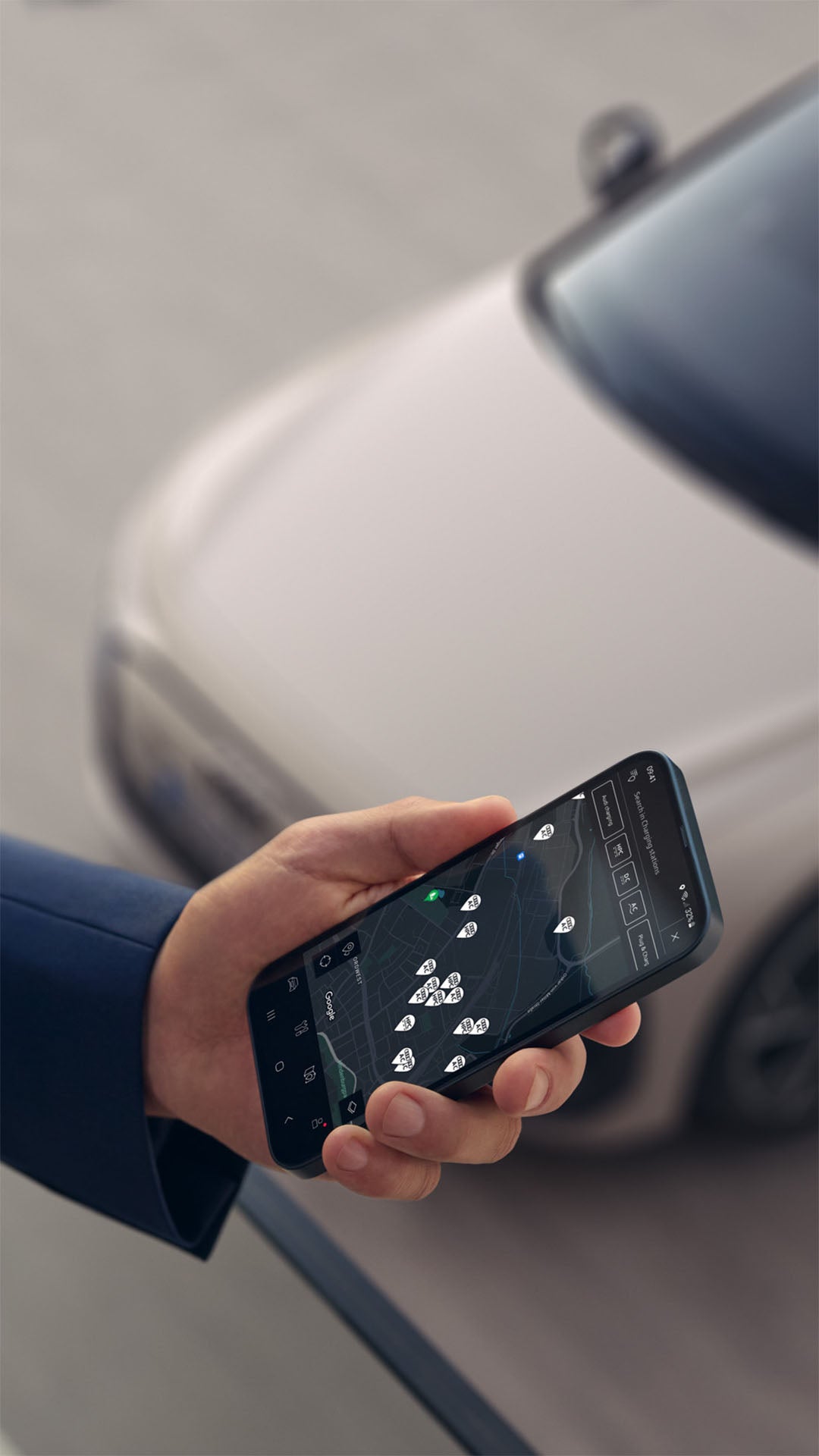 En person håller i en smartphone. I bakgrunden står en parkerad A6 Avant e-tron.