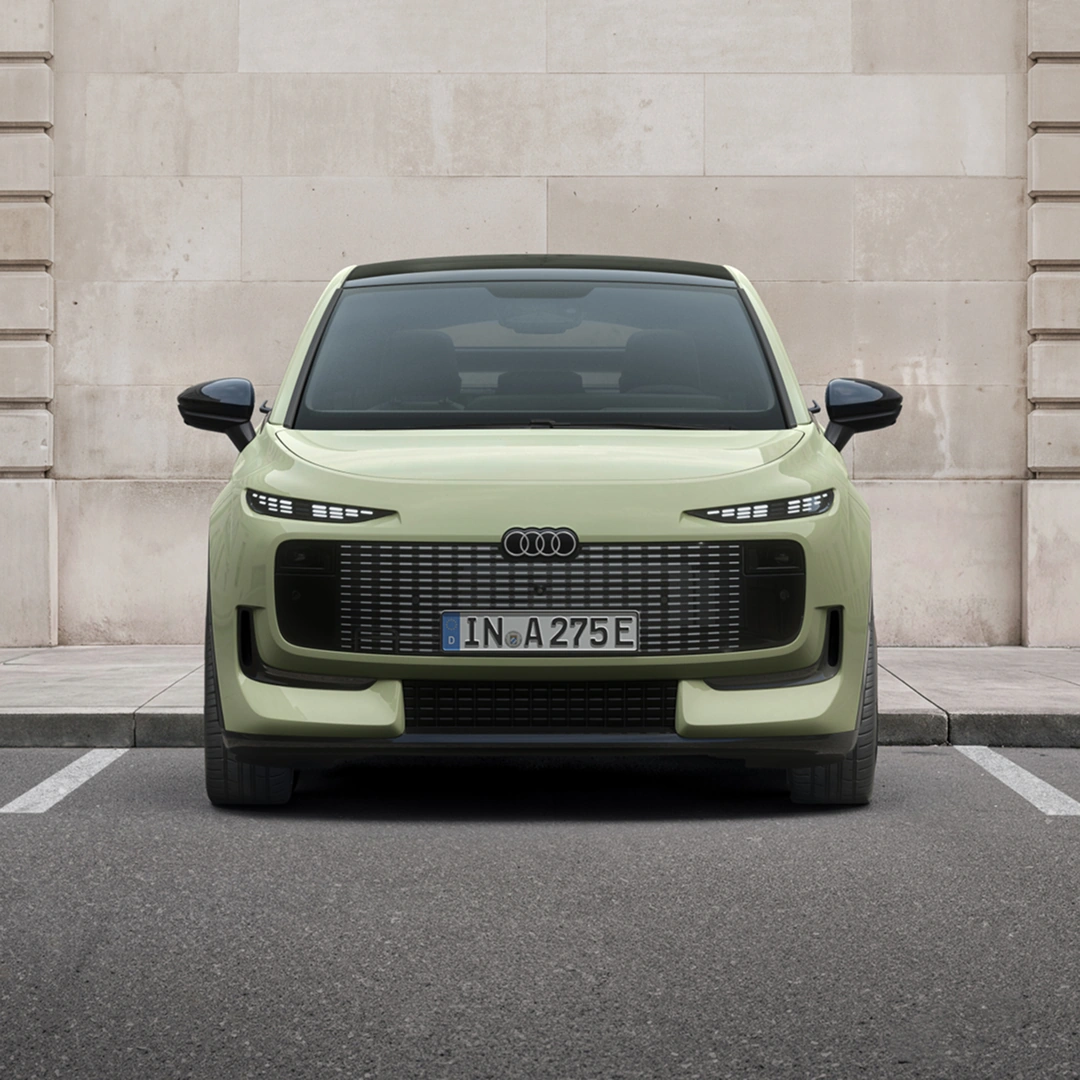 Overhead view of a light green Audi A2 e-tron electric hatchback driving on an urban street