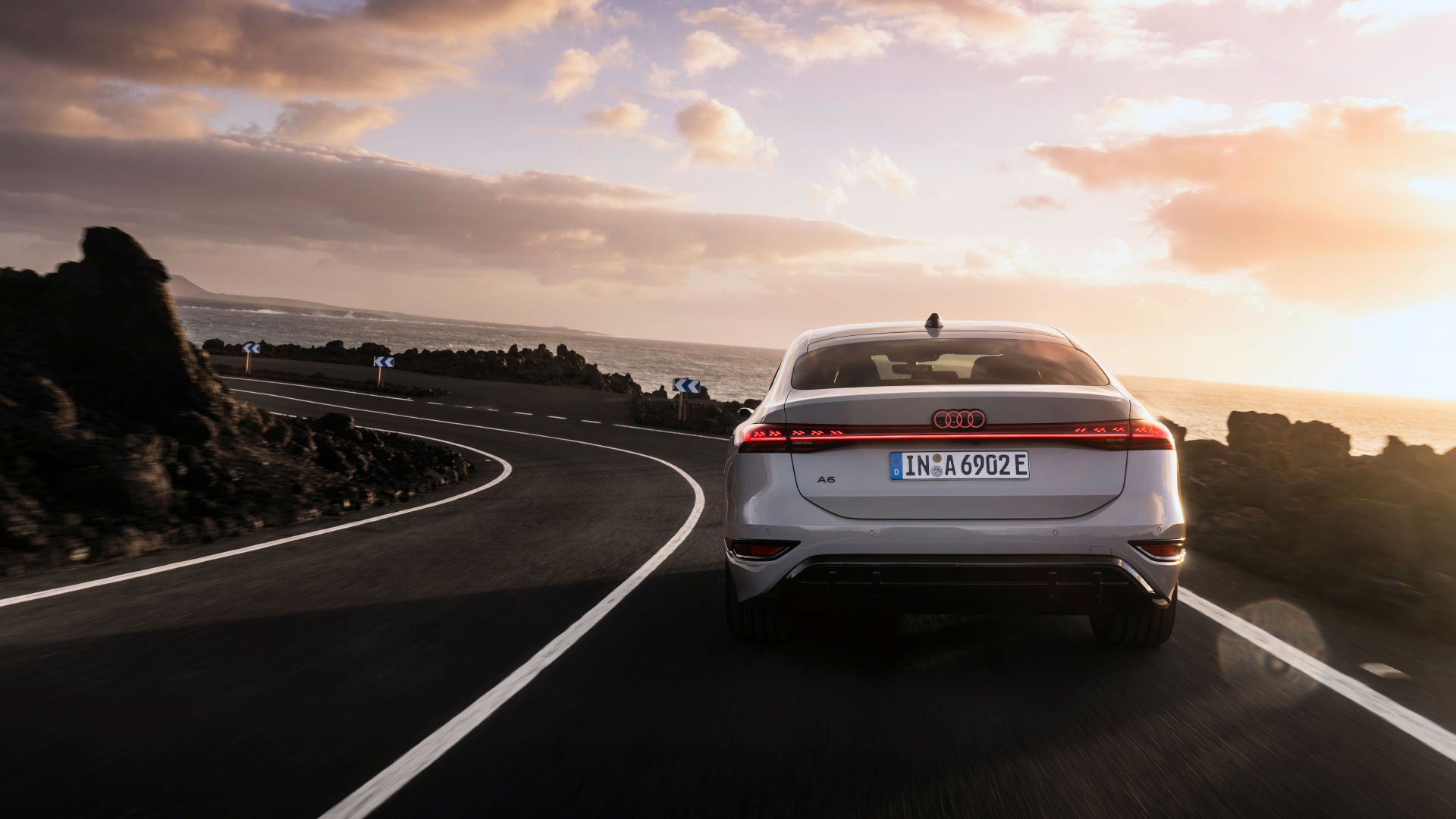 Audi A6 e-tron fährt auf einer Landstraße bei Abendrot