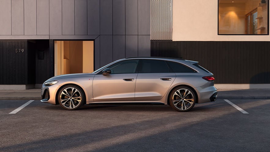 Ein grauer Audi A5 ist vor einem modernen Gebäude geparkt.