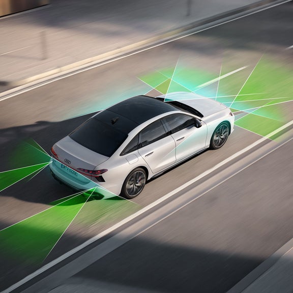 The A6 Saloon e-hybrid viewed from an elevated angle. Green and blue vectors extending from the rear and front divide the areas behind and in front of the vehicle.