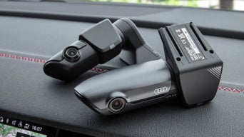 Audi Dashcam UTR 2.0 liegt auf schwarzem Dashboard mit roten Nähten.