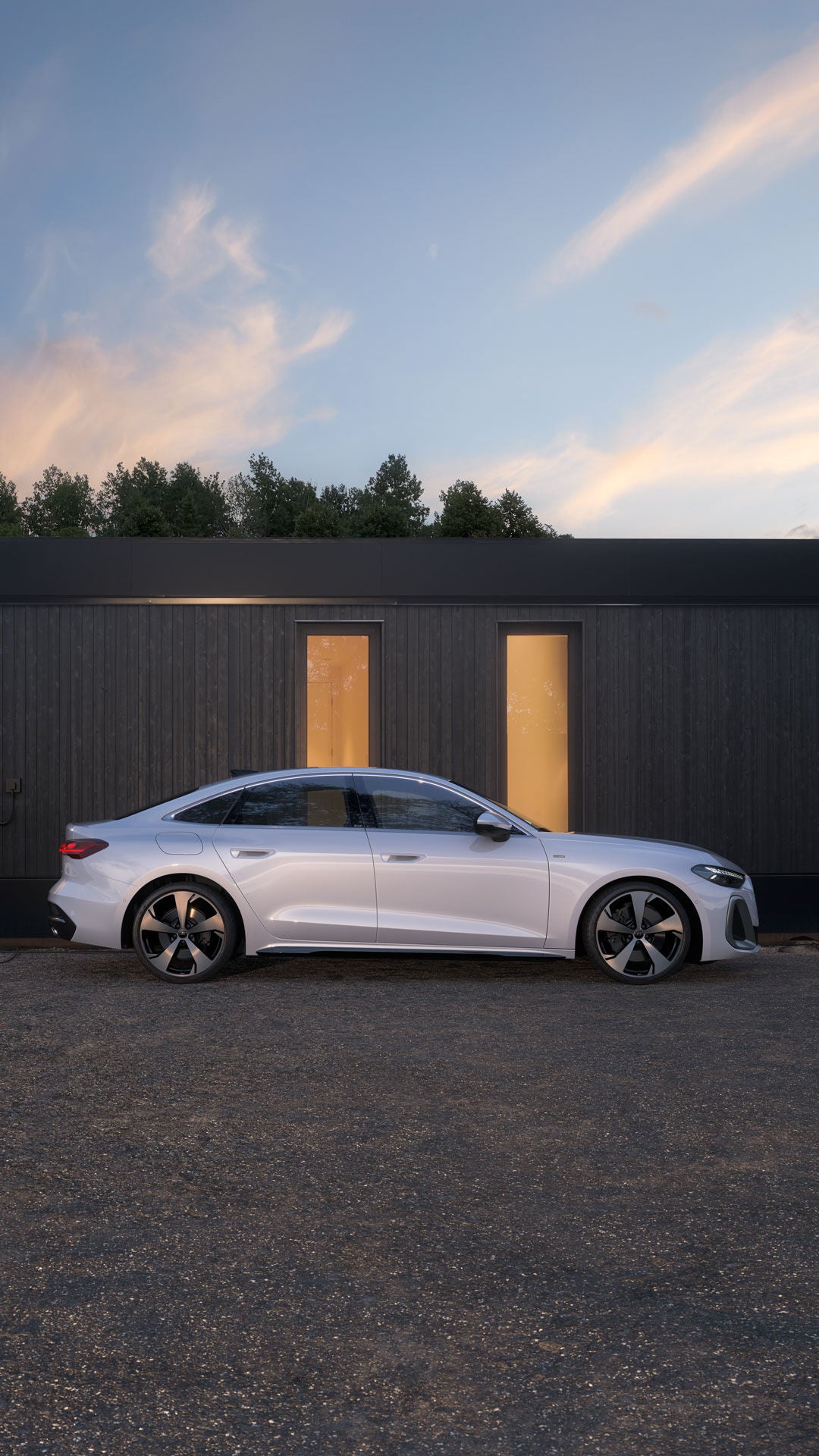 Mann vor modernem Haus neben einer weißen A5 e-hybrid Limousine, die an einer Wallbox-Ladestation angeschlossen ist, bei Abenddämmerung.