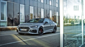 Grey Audi model parked outside a modern building