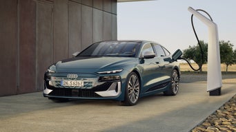 The S6 Sportback e-tron in a slanted front profile while connected to a charging station.