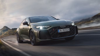 Een groene Audi RS 5 Limousine rijdt over een snelweg met bergen op de achtergrond