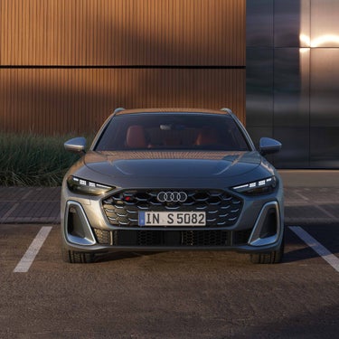 Frontansicht eines silbernen Audi S5 Avant vor einer modernen Fassade.
