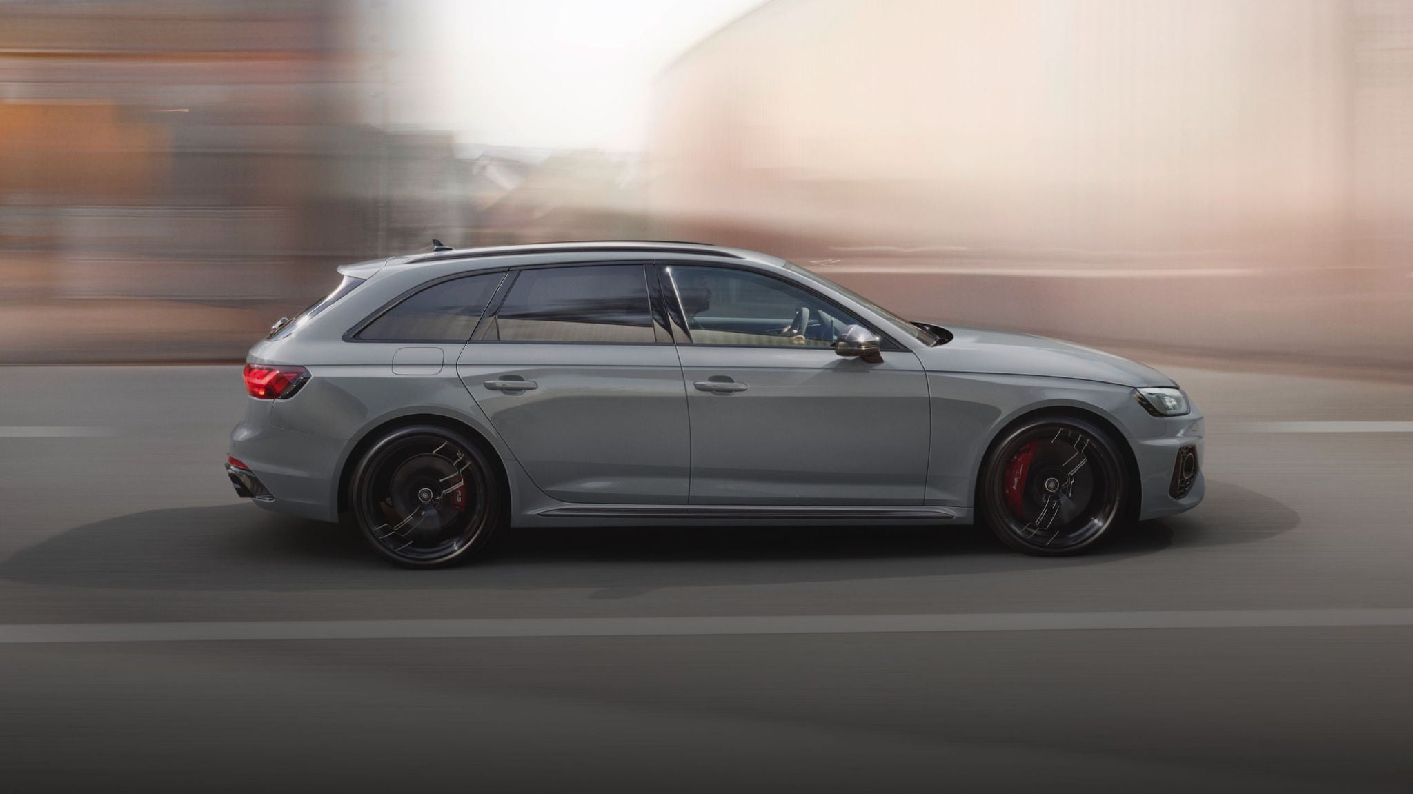 A grey car in motion on an urban road, with blurred background.