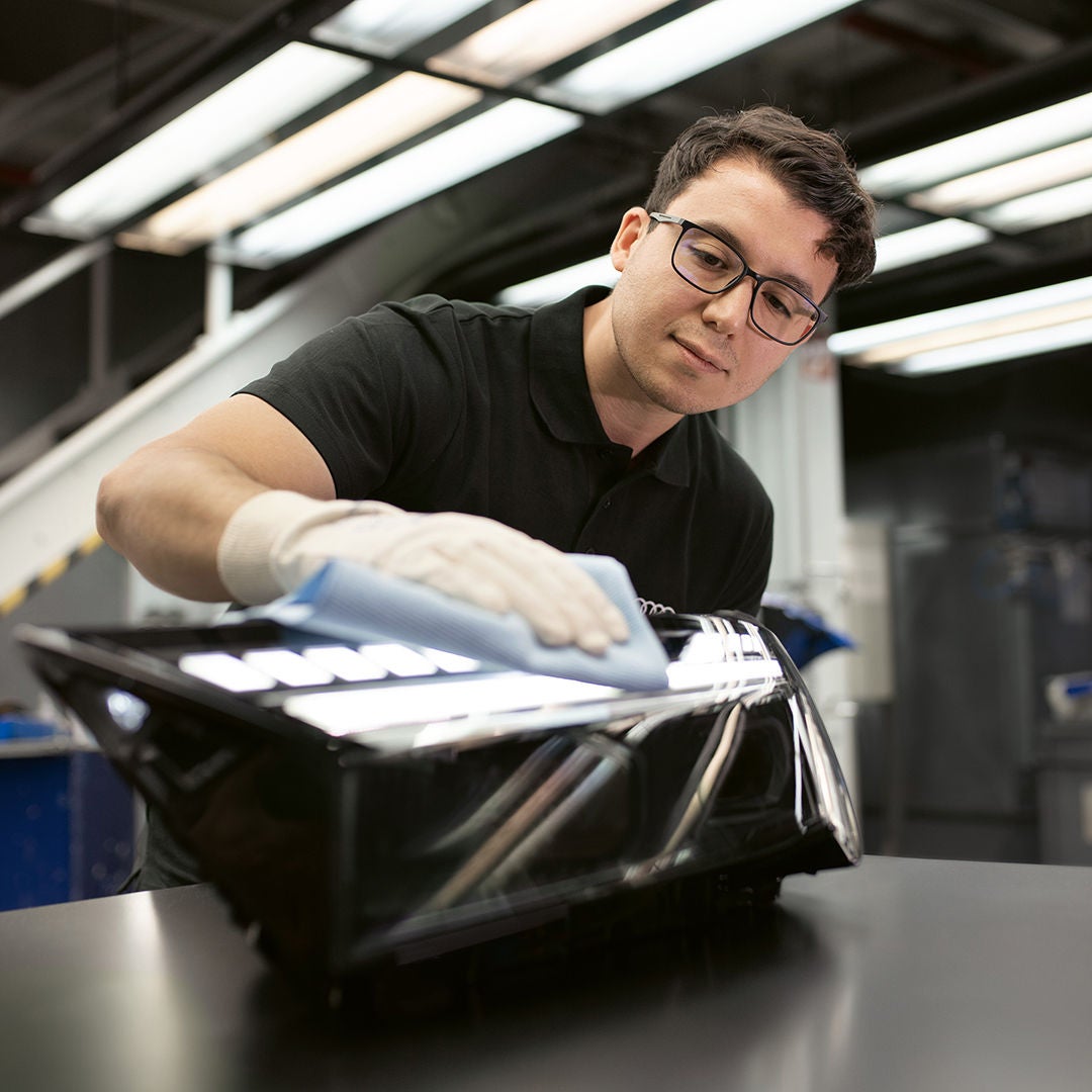 Un uomo lucida uno dei ricambi ricondizionati Audi con attenzione.         