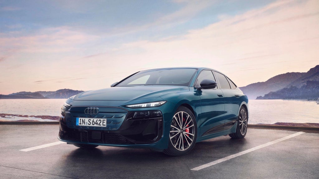 The S6 Sportback e-tron in a slanted front profile as it drives along a coastal road.