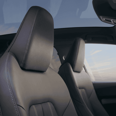 Close-up of a car's leather seats with a blurred skyline in the background.