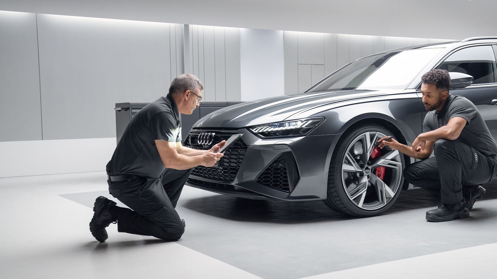 Dimostrazione del servizio Garanzia Audi Time Plus, con due uomini che riparano un veicolo Audi.