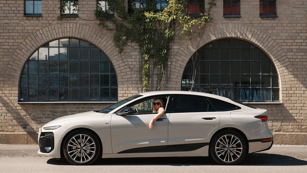 Helen Dahlberg i sin Audi A6 Sportback e-tron med en tegelbyggnad i bakgrunden