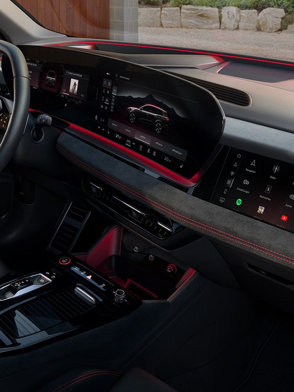 Cockpit mit durchgehendem digitalen Display, roter Ambientebeleuchtung, Multifunktionslenkrad und Anzeige eines Audi Fahrzeugs.