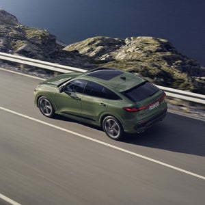 Der Q5 Sportback im schrägen Seitenprofil von oben betrachtet. Das Fahrzeug fährt auf einer Gebirgsstraße.