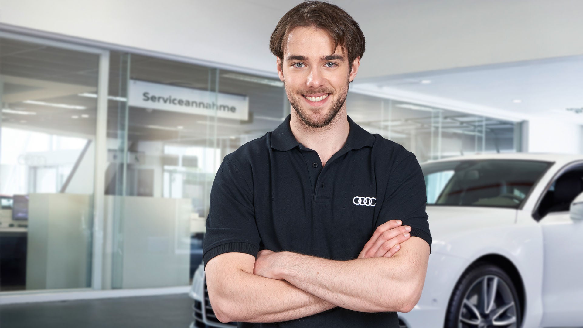 Diagnosetechniker steht vor einem weißen Audi und lächelt in die Kamera.