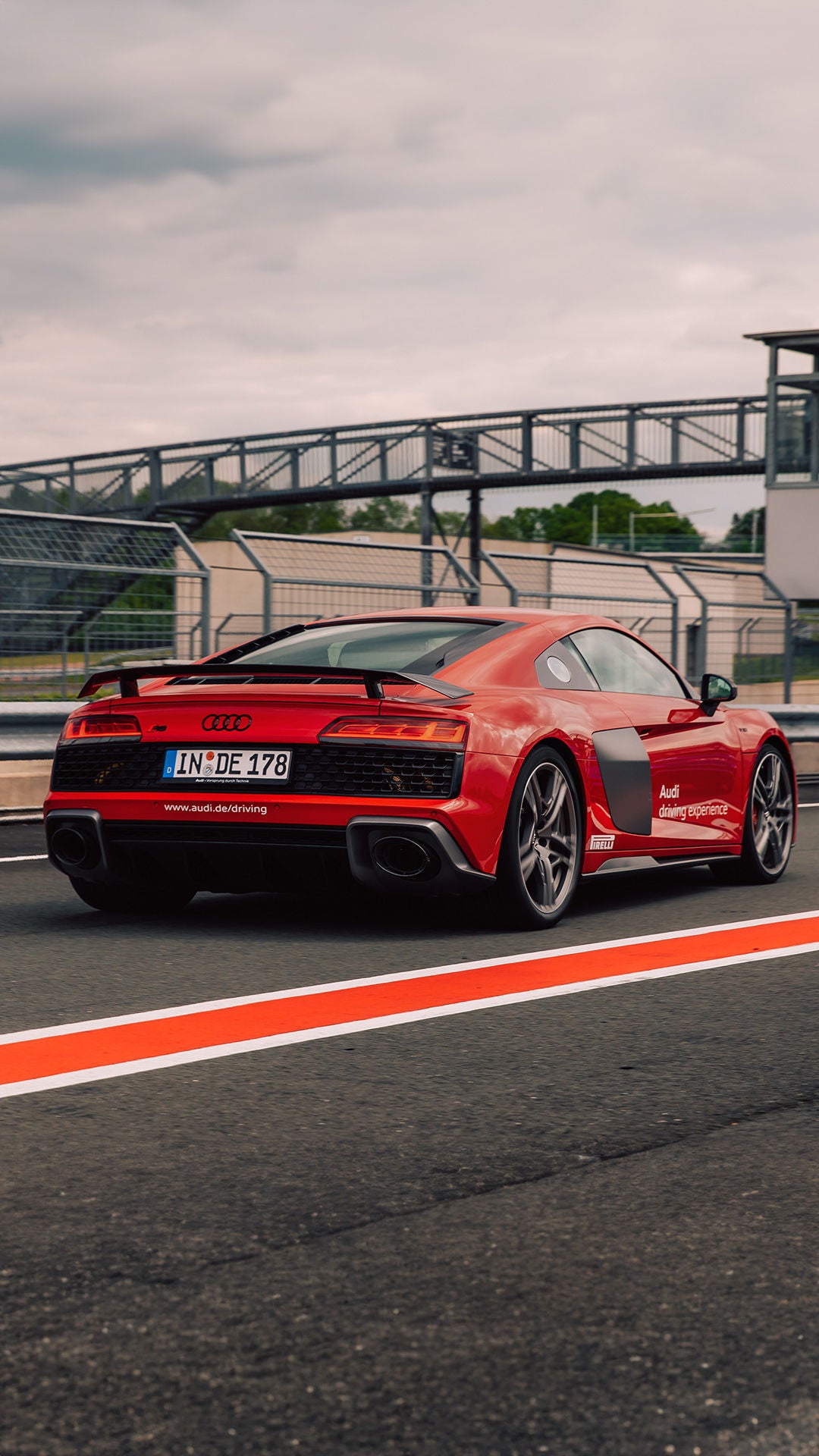 Roter Audi R8 Coupé V10 performance quattro auf einer Rennstrecke (Rückansicht).