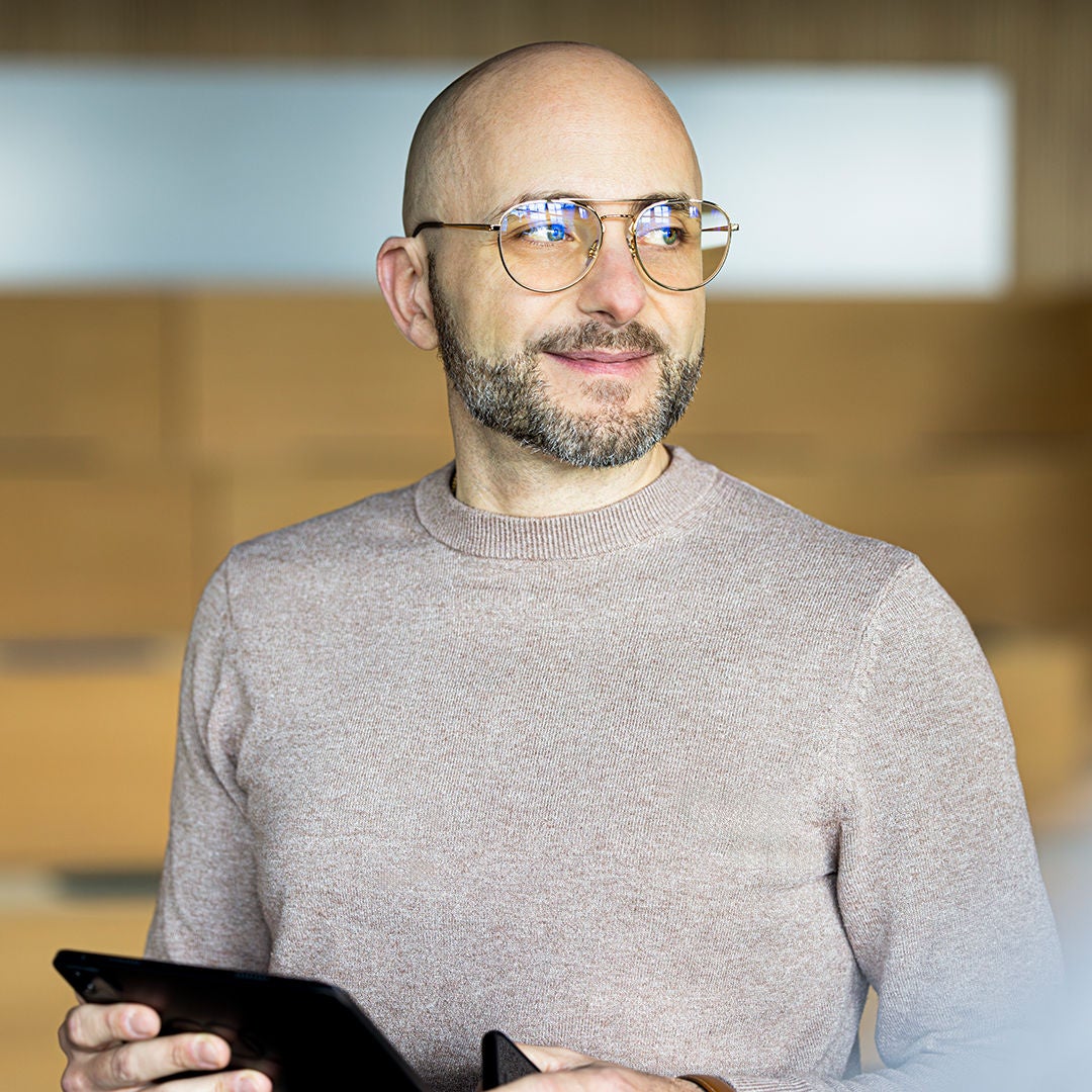 Mario schaut rechts an die Kamera vorbei und trägt eine Brille