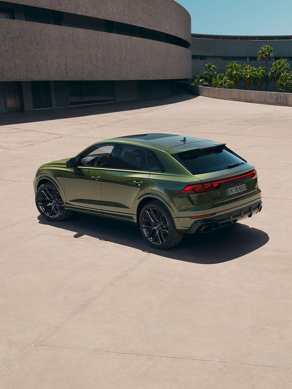 Ein grüner Audi RS Q8 SUV von schräg hinten fotografiert auf heller Betonfläche.