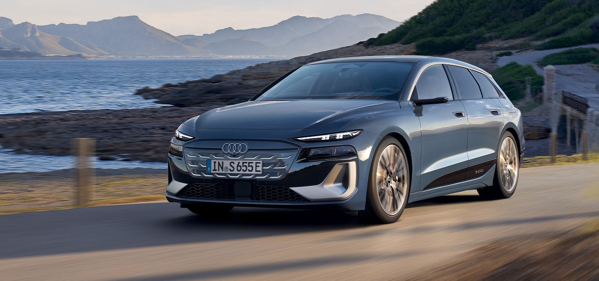 S6 Avant e-tron sedd framifrån, kör på en väg. Berg och hav i bakgrunden.