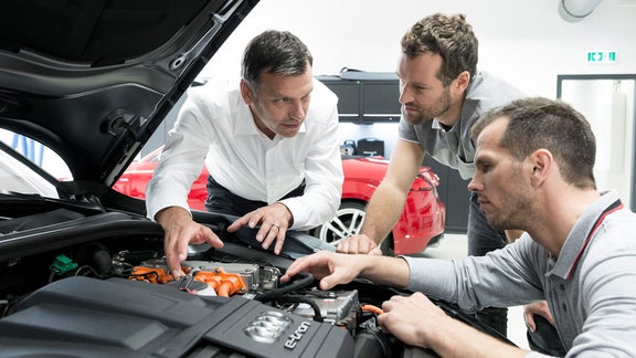 Drei Männer schauen unter die Motorhaube eines Audi e-tron.