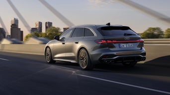 Der S5 Avant im schrägen Heckprofil, während er auf einer Straße auf eine Stadt zufährt.