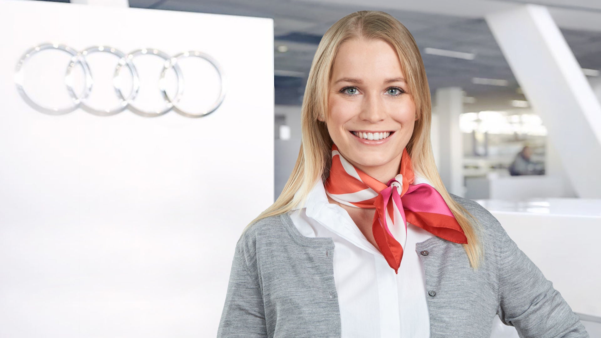 Im Autohaus steht eine Mitarbeiterin und lächelt in die Kamera.
