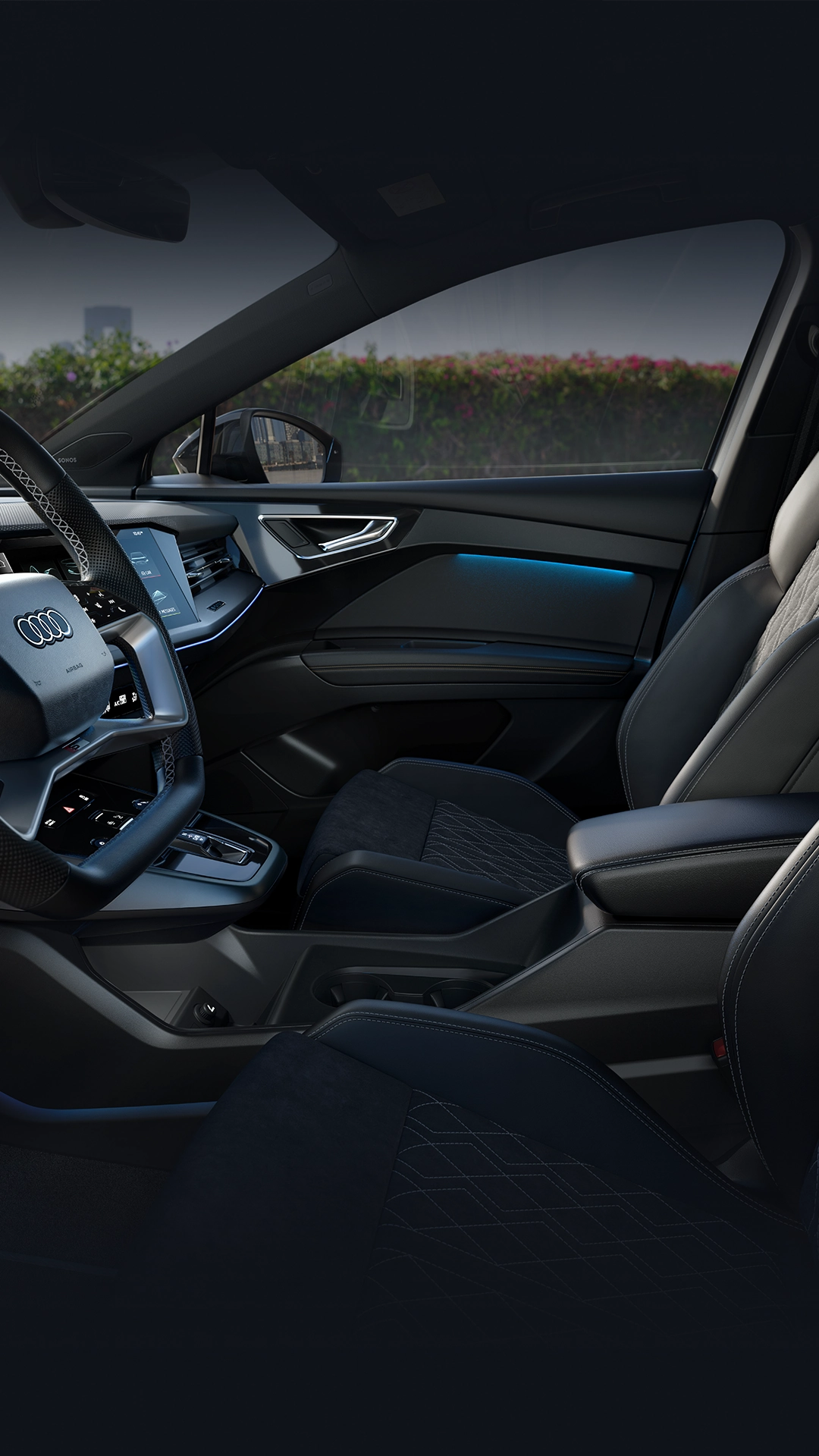 Audi Q4 e-tron interior, black leather and alcantara seats, steering wheel with Audi logo, centre console and dashboard visible.