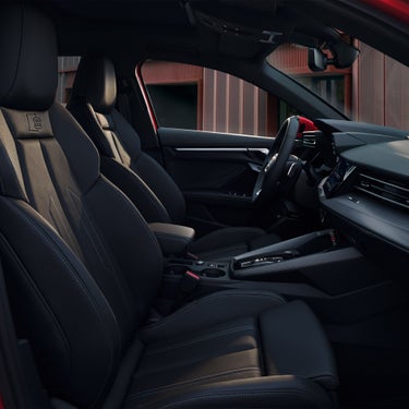 Schwarze Sportsitze mit hellem Kontrastnähren im Innenraum eines Audi-Fahrzeugs, Blick auf Armaturenbrett.